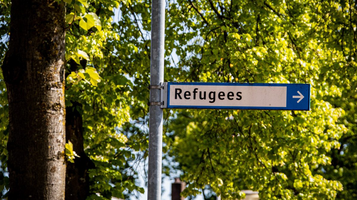 Verkeersborden bij een bushalte met daarop 'refugees'