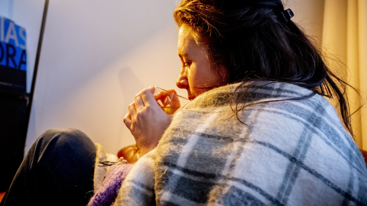 Vrouw met deken in de woonkamer, de verwarming moest vorig jaar winter lager vanwege de hoge kosten. Ter illustratie. Beeld: ANP