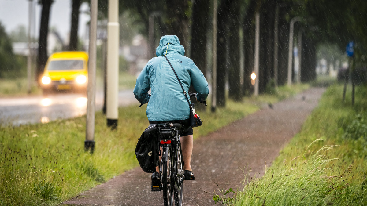 Iemand fietst door een regenbui, ter illustratie. Beeld: ANP