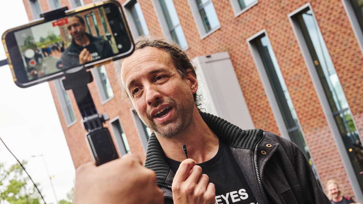 Willem Engel met microfoontje in zijn hand bij gebouw Facebook