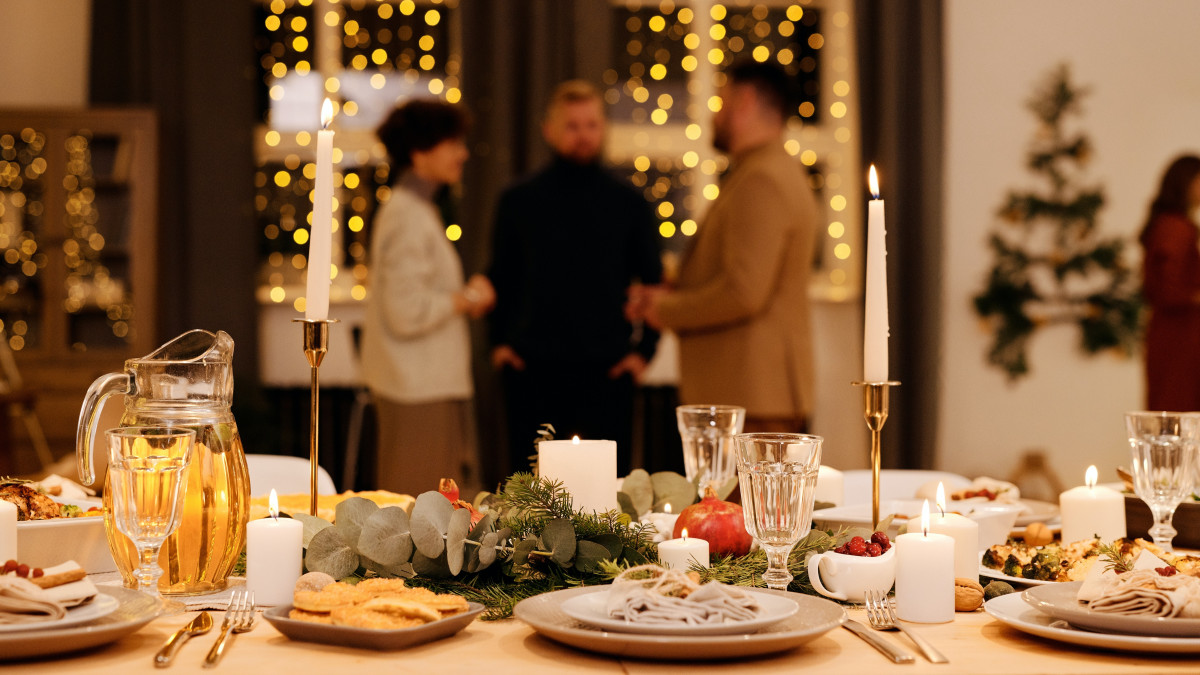 Kerstdiner op tafel met eten en drinken, gezelschap op achtergrond (Pexels)