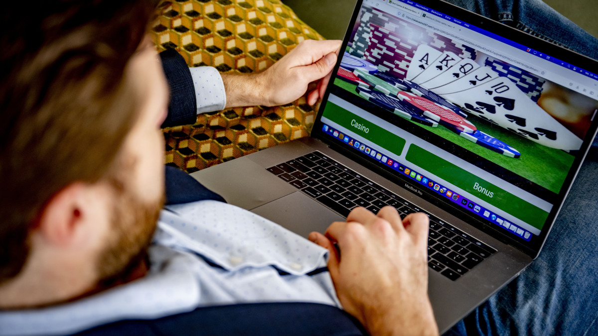 Een man waagt een gokje in een online casino achter een laptop - Beeld: ANP