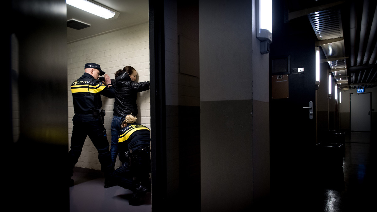 Een vrouw wordt gefouilleerd door agenten op het politiebureau (ANP, ter illustratie)